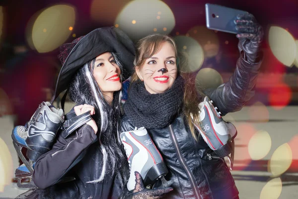 Dvě šťastné ozdobný oblečené dívky, aby selfie na mobil — Stock fotografie
