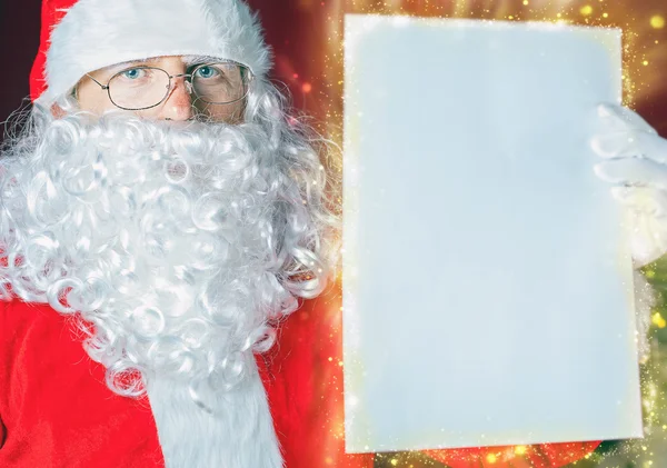 Santa Claus sosteniendo una lista de deseos, carta blanca o papel . —  Fotos de Stock