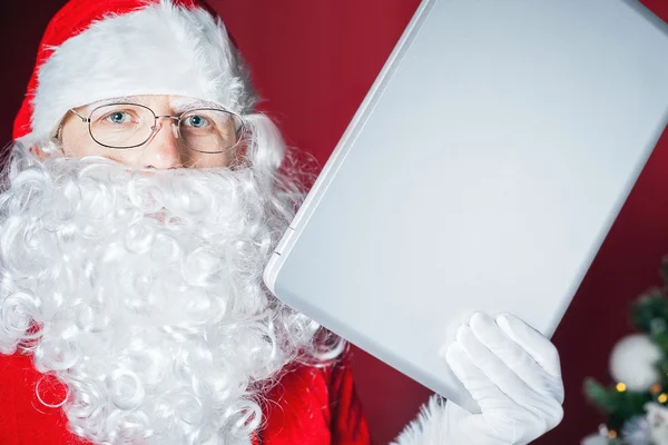 Papai Noel segurando um computador portátil — Fotografia de Stock