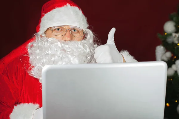 Santa Claus innehar en bärbar dator — Stockfoto