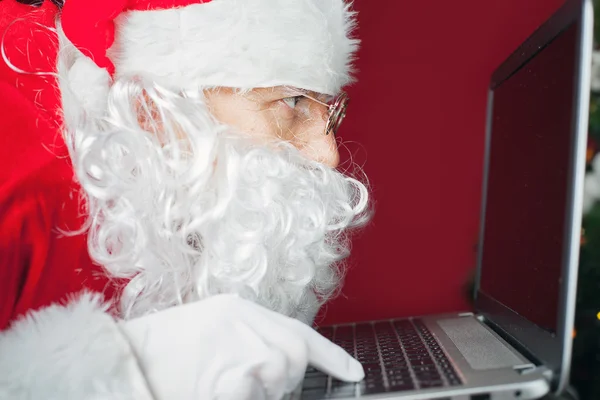Santa Claus usando ordenador portátil, mirando a la pantalla — Foto de Stock