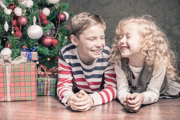 Menino e menina deitados no chão sob a árvore de Natal — Fotografia de Stock