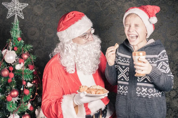 Σάντα και αστεία αγόρι με μπισκότα και γάλα για τα Χριστούγεννα — Φωτογραφία Αρχείου