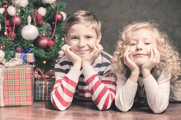 Menino e menina deitados no chão sob a árvore de Natal — Fotografia de Stock