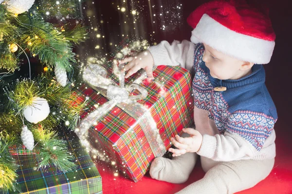 Vacanze di Natale. Bambino in Santa cappello scatola di apertura di regali — Foto Stock