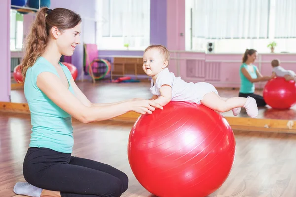 Mãe com bebê feliz fazendo exercícios com bola de ginástica — Fotografia de Stock