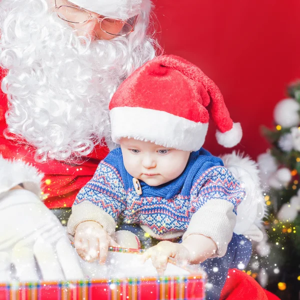 Natal bebê e Papai Noel abrindo um presente ou caixa de presente — Fotografia de Stock
