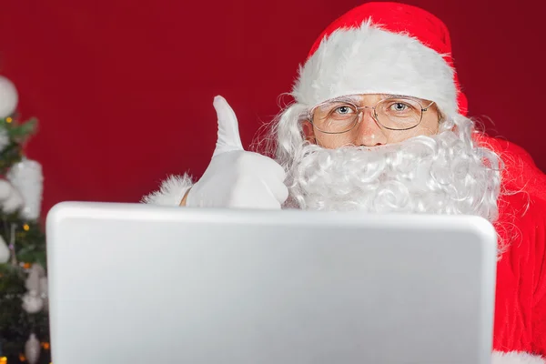 Santa Claus sosteniendo un ordenador portátil — Foto de Stock