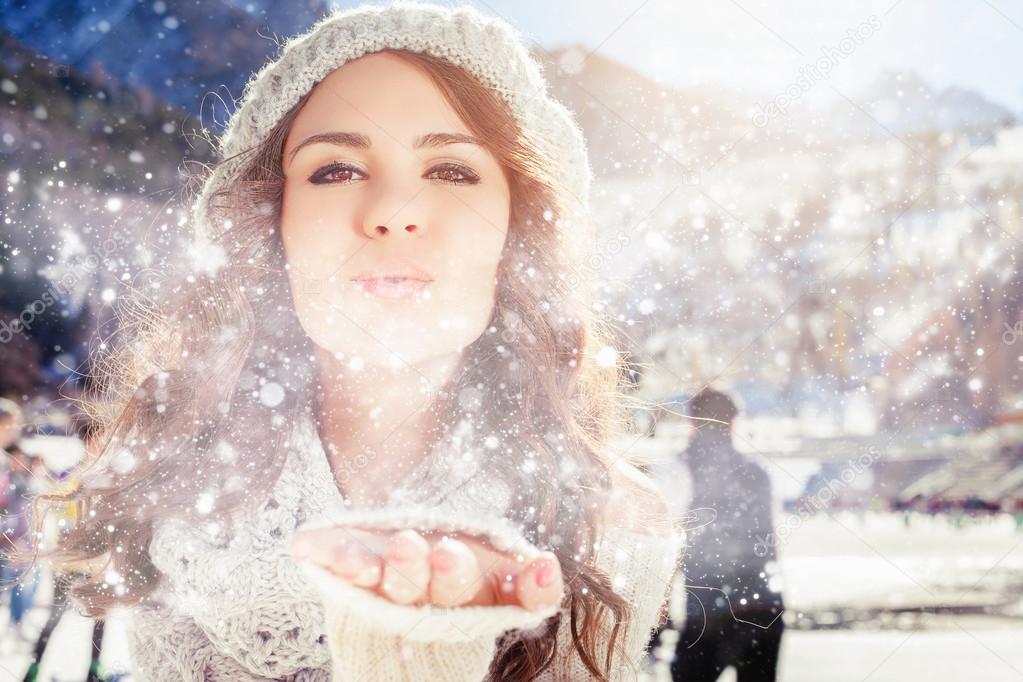 Beautiful girl blowing of snow and snowflakes, winter