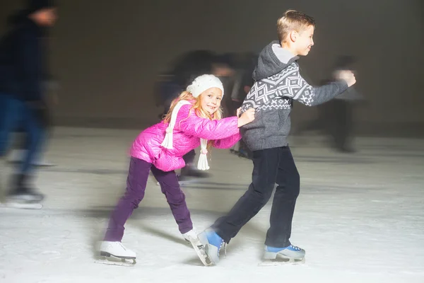 Szczęśliwe dzieci na łyżwach na lodowisku, zimowych nocy — Zdjęcie stockowe