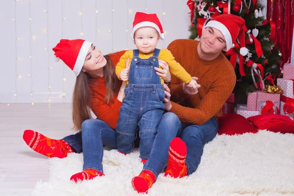 Lycklig familj på julafton sitter tillsammans nära dekorerade träd — Stockfoto