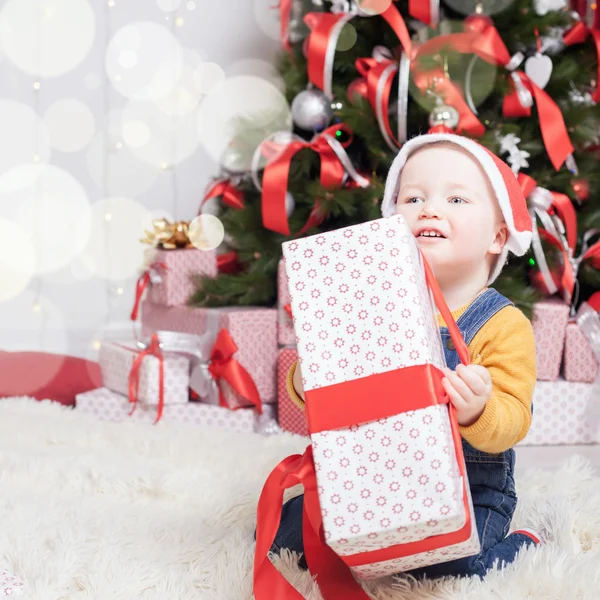Vicces baba ül a karácsonyfa közelében sok ajándék doboz — Stock Fotó