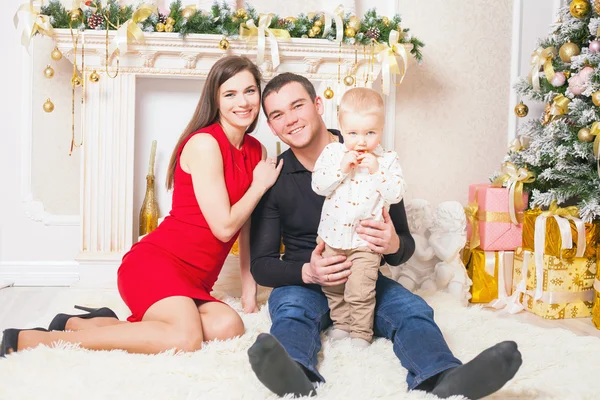 Família feliz na véspera de Natal sentado junto perto da lareira — Fotografia de Stock