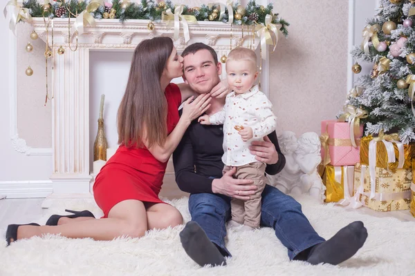 Família feliz na véspera de Natal sentado junto perto da lareira — Fotografia de Stock