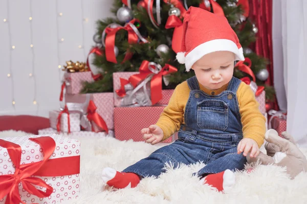 Engraçado bebê sentado perto da árvore de natal com muitas caixas de presente — Fotografia de Stock