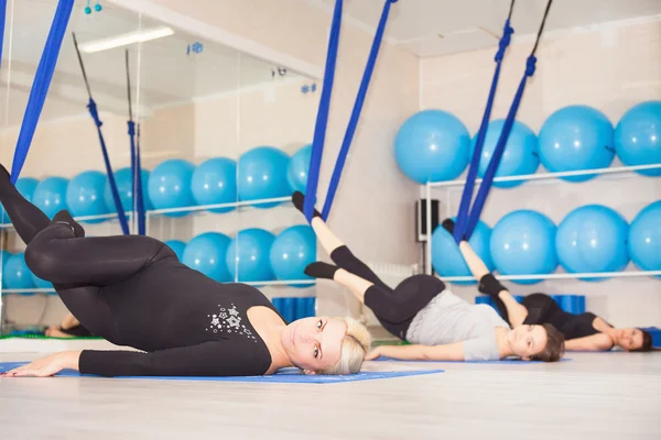 Mujeres jóvenes haciendo ejercicio de yoga aéreo o yoga antigravedad —  Fotos de Stock