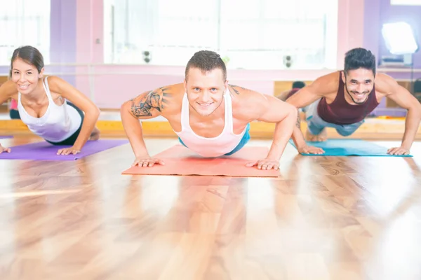 Dos jóvenes hombres y asiático chica haciendo flexiones interior —  Fotos de Stock