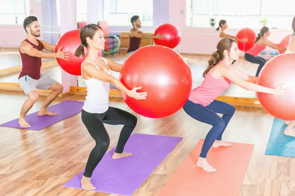 Vackra raser kvinnor och man gör övning med gimnastic boll. — Stockfoto