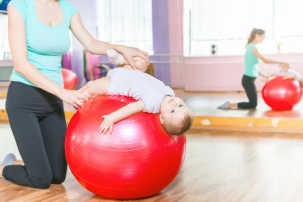 Jimnastik topu ile egzersizleri yapıyor mutlu bebek ile anne - Stok İmaj