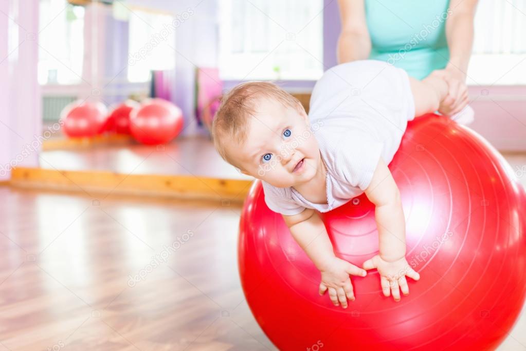 Mother with happy baby doing exercises with gymnastic ball