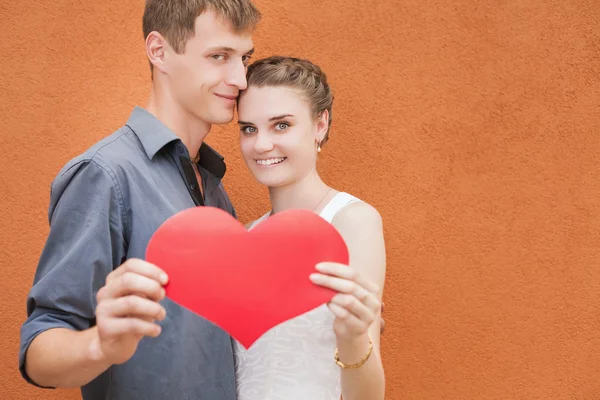 Happy couple holding a big heart symbol — Stock Photo, Image