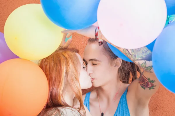 Молодая счастливая пара целуется и держит воздушные шары — стоковое фото
