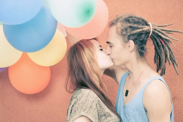 Young happy couple kissing and holding balloons — Stock Photo, Image