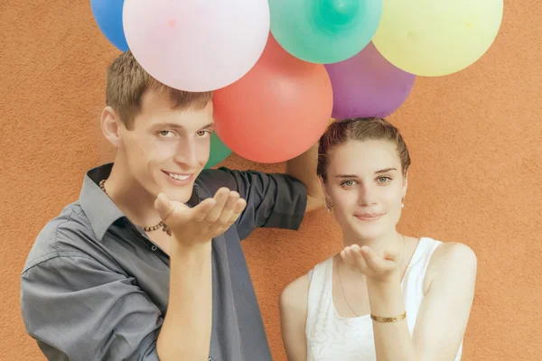 Joven feliz pareja besando y sosteniendo globos — Foto de Stock