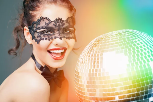 Молодая сексуальная женщина в карнавальной маске держит диско мяч — стоковое фото