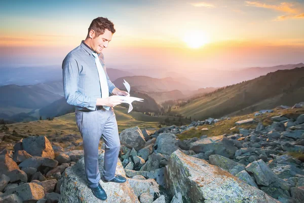 Young businessman sits on top of the mountain — Stock Photo, Image