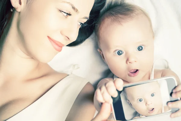 Divertido bebé y madre hacen selfie en el teléfono móvil —  Fotos de Stock