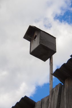 Mavi Gökyüzü bulutlu bir arka plan üzerinde ahşap kuş yuvası