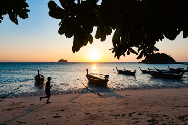 Praia de manhã com homem correndo e barco com nascer do sol em L — Fotografia de Stock