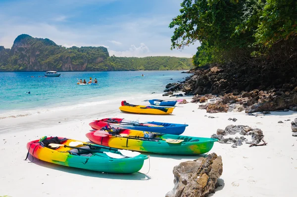 Caiaques coloridos na praia com turista atrás e os barcos — Fotografia de Stock