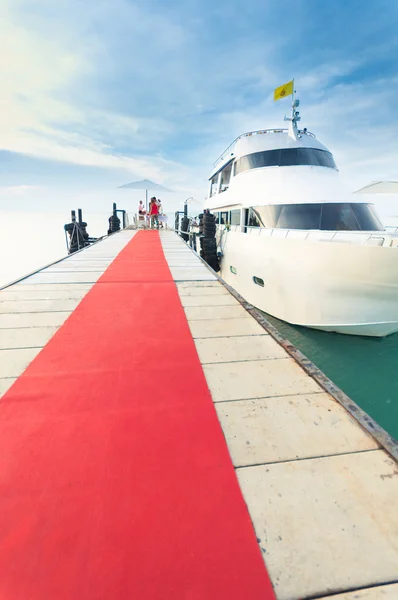 Yacht docking at the pier with red carpet to party — Stock Photo, Image