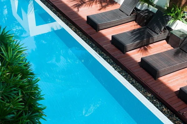 Zwembad met donkere stoelen naast — Stockfoto