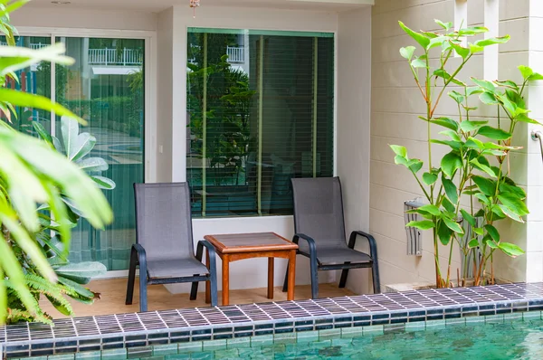 Cadeiras e mesa montadas atrás da sala com acesso à piscina — Fotografia de Stock