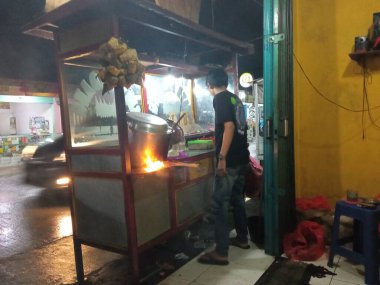 Satay satıcısı alıcıya yemek hazırlıyor.