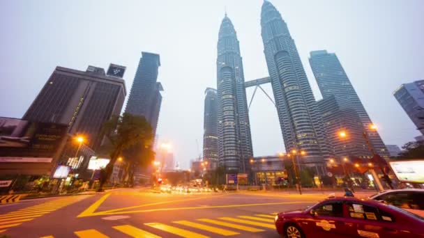 KUALA LUMPUR, MALAISIE - 17 OCTOBRE 2015 : Abandon du feu de circulation du carrefour 4k de la nuit au jour le jour à Suria KLCC avec les tours Petronas. Affichage des véhicules en mouvement pendant l'heure de pointe du matin. incliner vers le haut . — Video