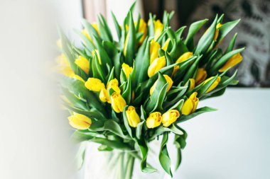 Pencerenin yanındaki vazoda güzel sarı çiçekler. Sarı lale çiçeklerinden bir kadına hediye..