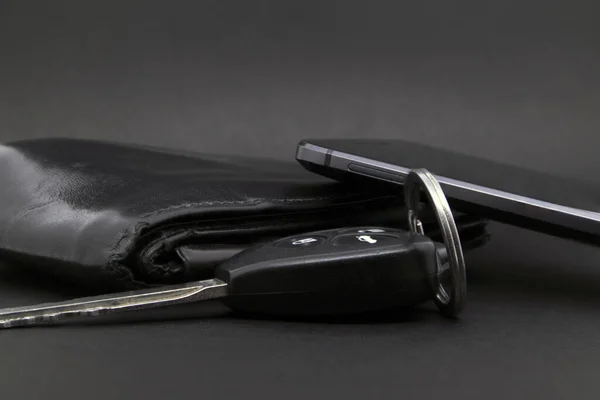 Wallet, phone and car keys on a dark background