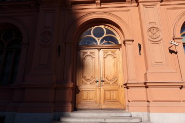 Üzerinde büyük bir gölge olan eski bir taş ev. Büyük ahşap kapılar.