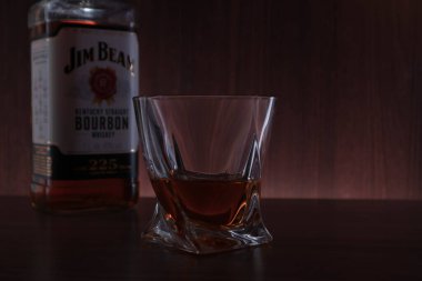 Bir bardak burbon ve bir şişe Jim Beam. Riga, Letonya - 19 Mar 2021