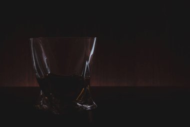 Karanlıkta masada bir bardak burbon.