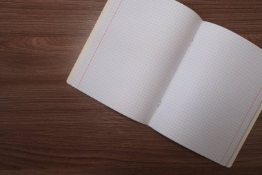 Kahverengi ahşap bir masanın üzerinde boş bir kare defter..