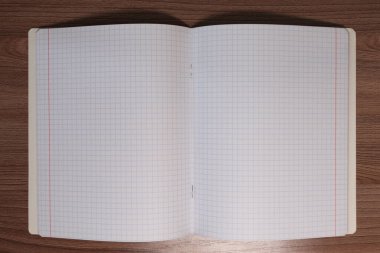 Kahverengi ahşap bir masanın üzerindeki kareli defter..