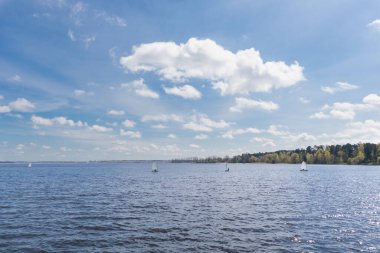 Mavi gökyüzü ve küçük yelkenli tekneli göl.