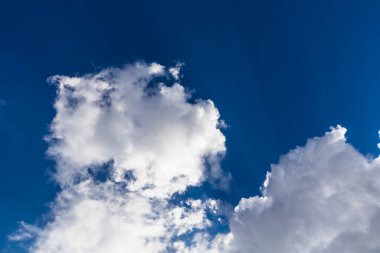 Mavi gökyüzünde büyük, beyaz kümülüs bulutları.