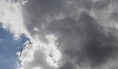 Gri yağmur bulutları mavi gökyüzünü kaplıyor.