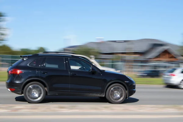 Hızlı hareket eden siyah Porsche Cayenne. Hareket bulanıklığı. Riga, Letonya - 14 Haziran 2021.